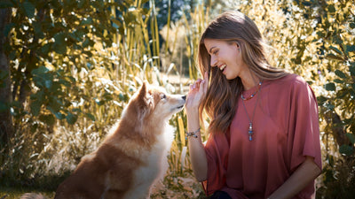 Woman playing with her dog in nature wearing Trollbeads jewellery from the love off Paws collection