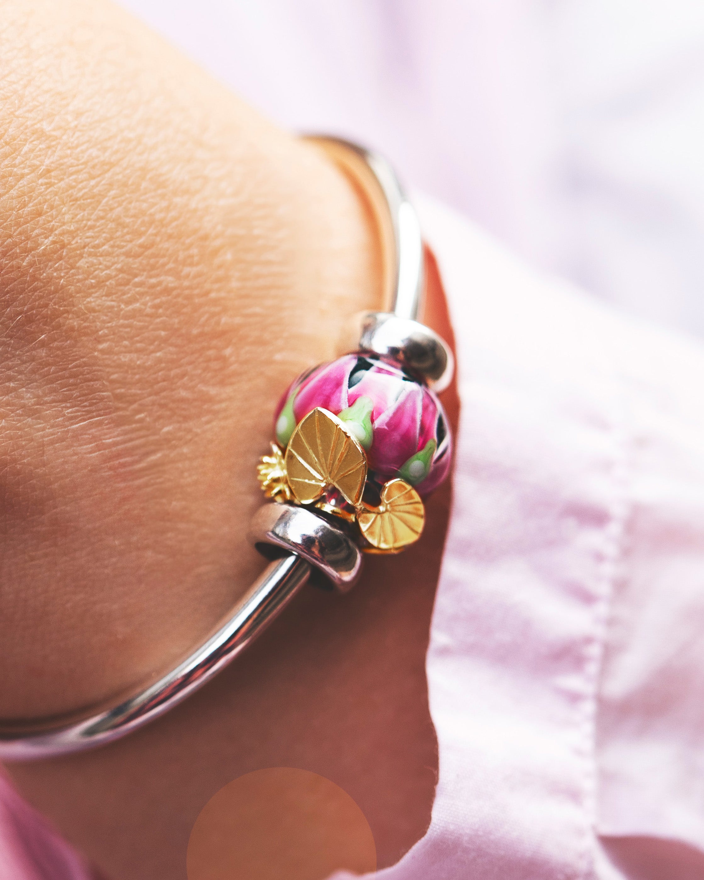 Silver bangle with gold plated bead and glass bead in pink